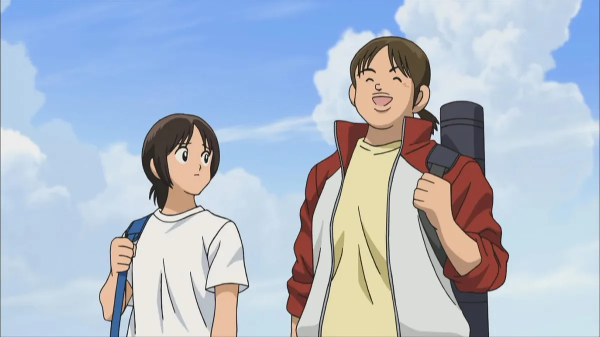 A boy in a white T-shirt and a taller boy in a red jacket carrying a bat case stand under summer clouds, in a still from Cross Game