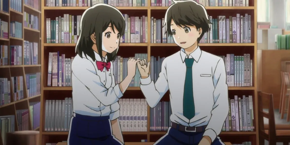 A girl and a boy in school uniforms link little fingers in a pinky promise in front of library shelves, in a still from Tsuki ga Kirei